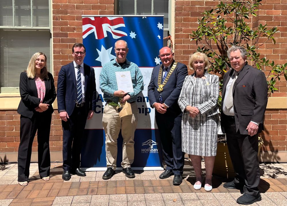 Tom showing off his certificate of citizenship alongside various local dignitaries 