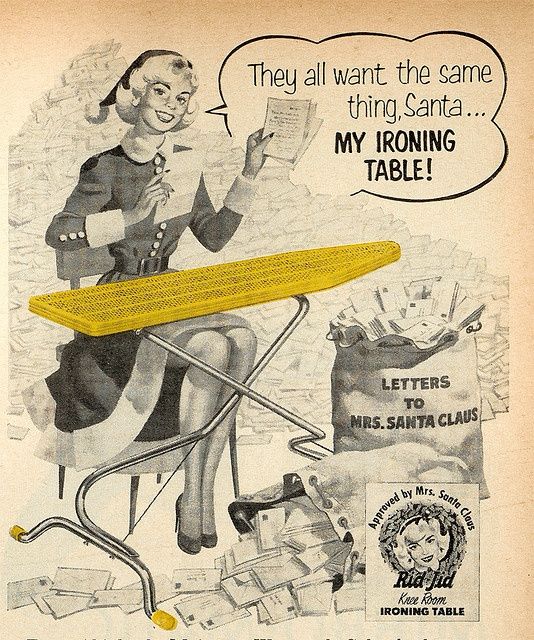 A 1950 ad of a lady wearing a Santa Hat sitting in front of an ironing board. A large mail sack with letters to Mrs. Santa Claus. 