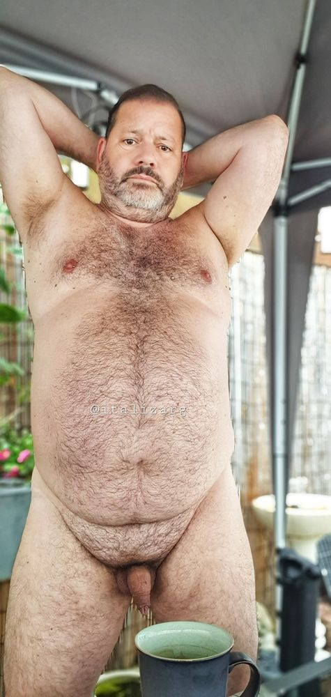 Italizarg naked in the courtyard in front of a cup of coffee hands behind his neck
