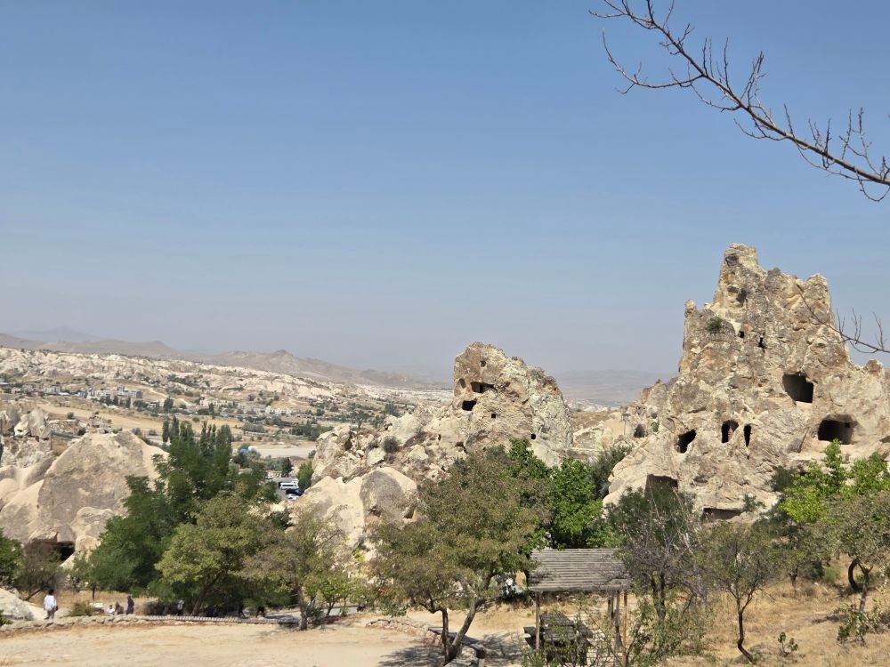 Looking out over the area. To the right are cave rocks - giant rock pillars with holes in them. The whole area is dusty but there is a blue sky
