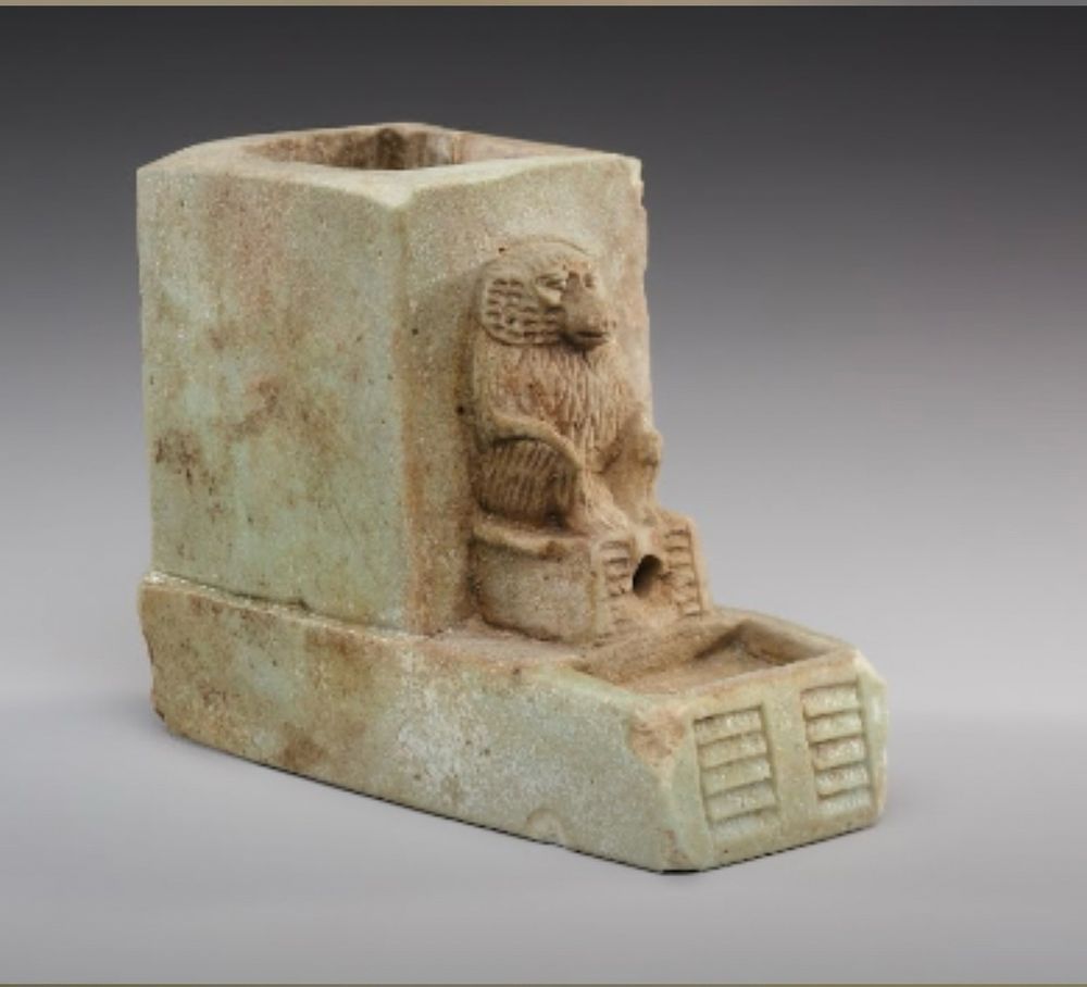 What looks like a marble water clock with a baboon carved on the front and the vessel for water in the back a beautiful kind of muted goldish white marble