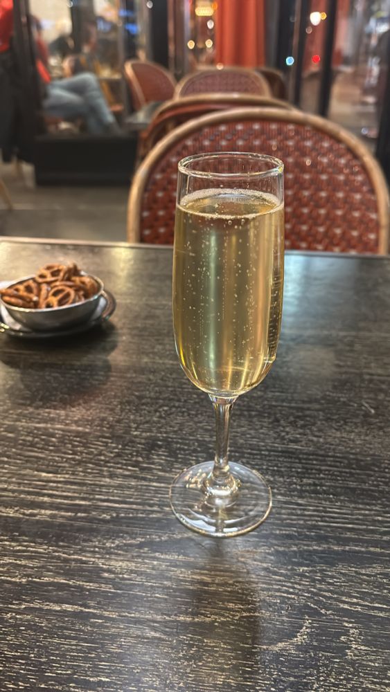 Une flute de champagne sur une table de bistrot et quelques biscuits secs dans un petit bol en métal.