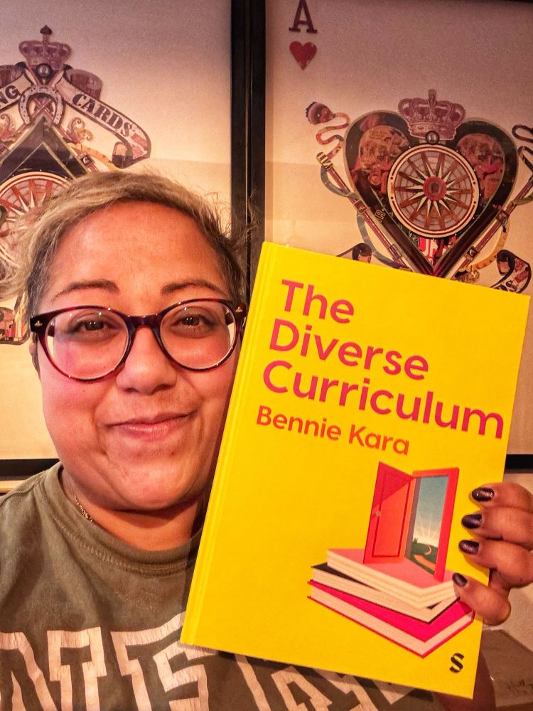 Bennie holding a hardback copy of The Diverse Curriculum and looking very smug. 