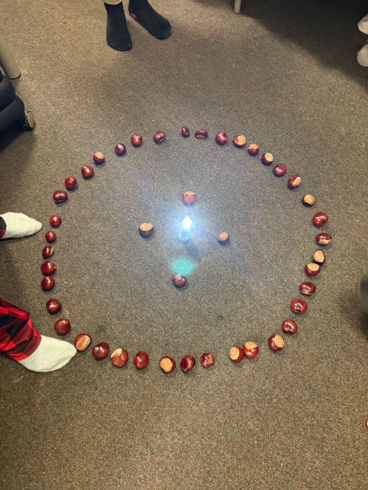 A circle of conkers with a torch in the middle