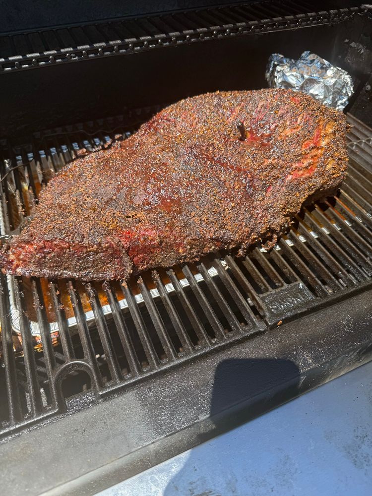 Picture of a beef brisket on a smoker halfway through cooking 
