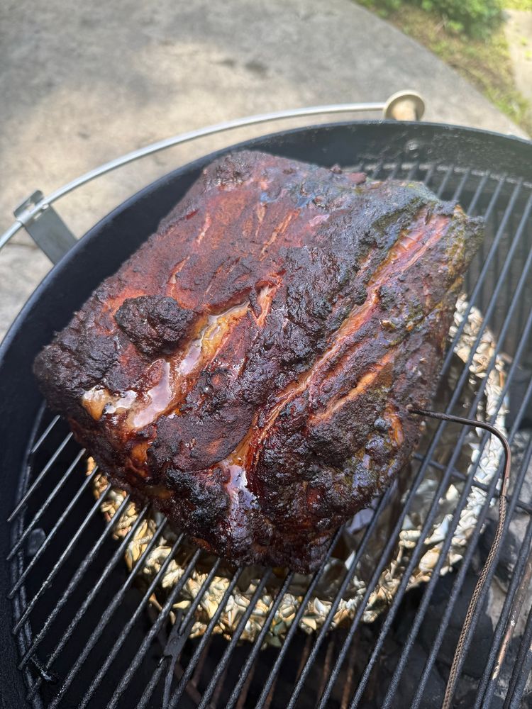 Picture of a smoked pork shoulder on a grill, about halfway through the process