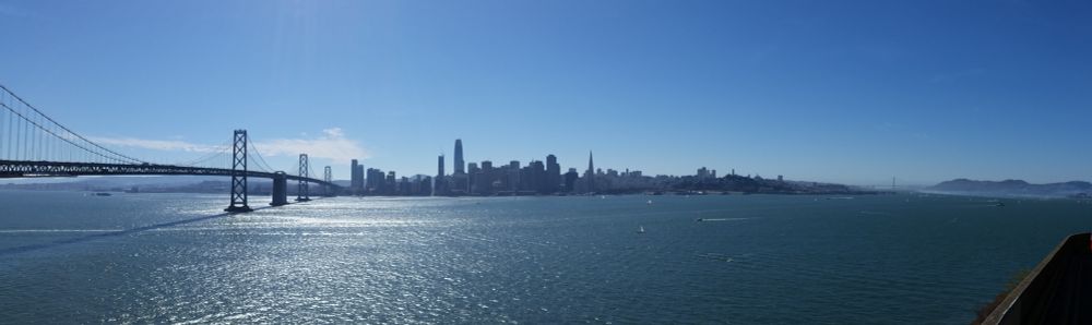 View of San Francisco from Treasure Island that also captures the SF/Oakland Bay Bridge and the Golden Gate Bridge.