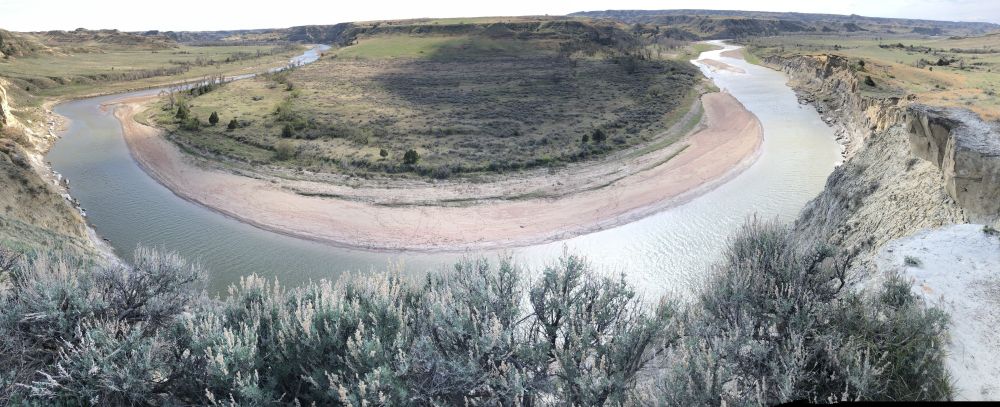 Panoramic photo of a wide oxbow in a river, as seen from high up on a cliff.