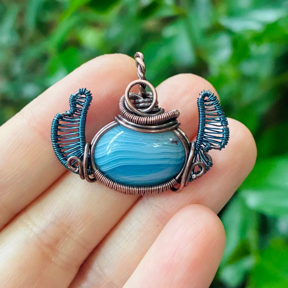 Copper wirewrapped pendant in the shape of stitch with a blue stone head and blue weaved ears