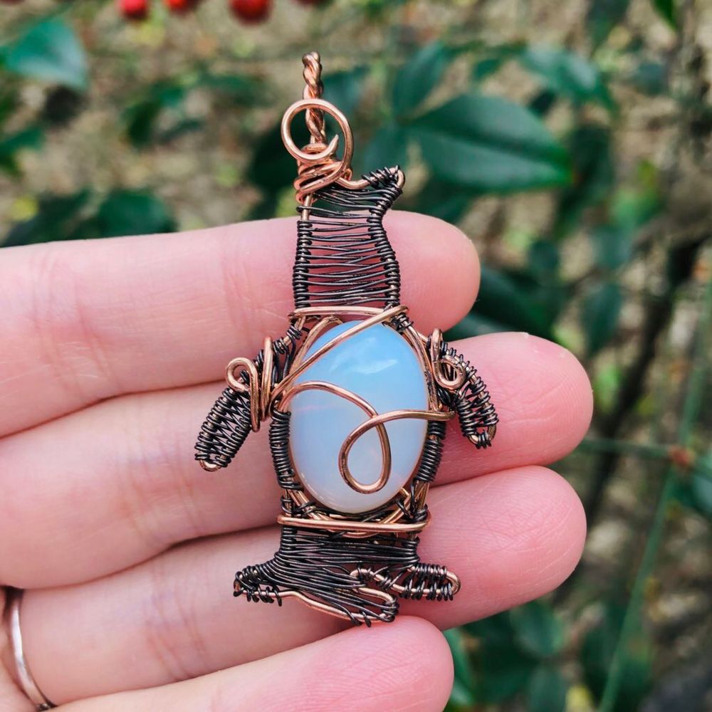 Copper wirewrapped pendant in the shape of a penguin with a milky white stone body & weaved head/legs/arms 