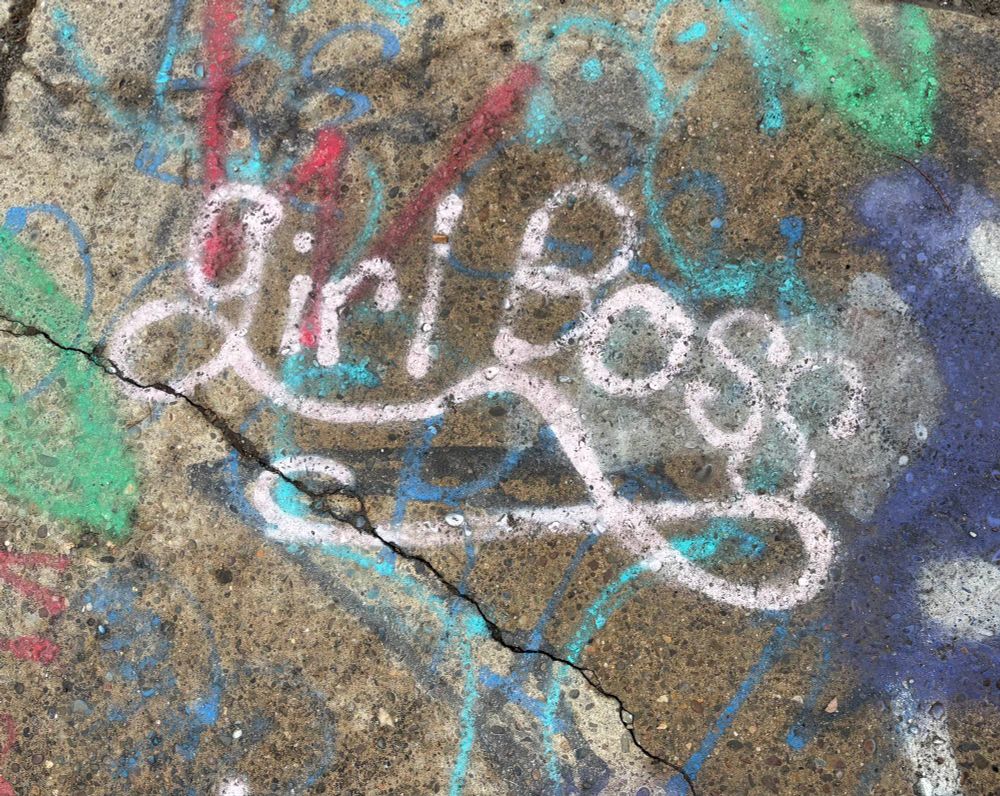 Heavily graffitied sidewalk with “girl Boss” written in white standing out. 