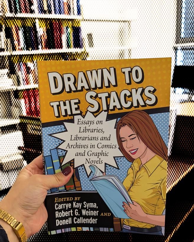 Holding the essay collection "Drawn to the Stacks" in a room of our library filled with bookshelves and a book cart. The background of the photo is made to look as if it was the cheap screen print of mid-century comicbooks