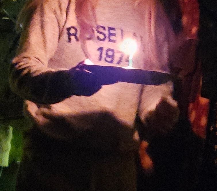 Nærbilde av noen som bærer en asjett med brownie med kakelys på