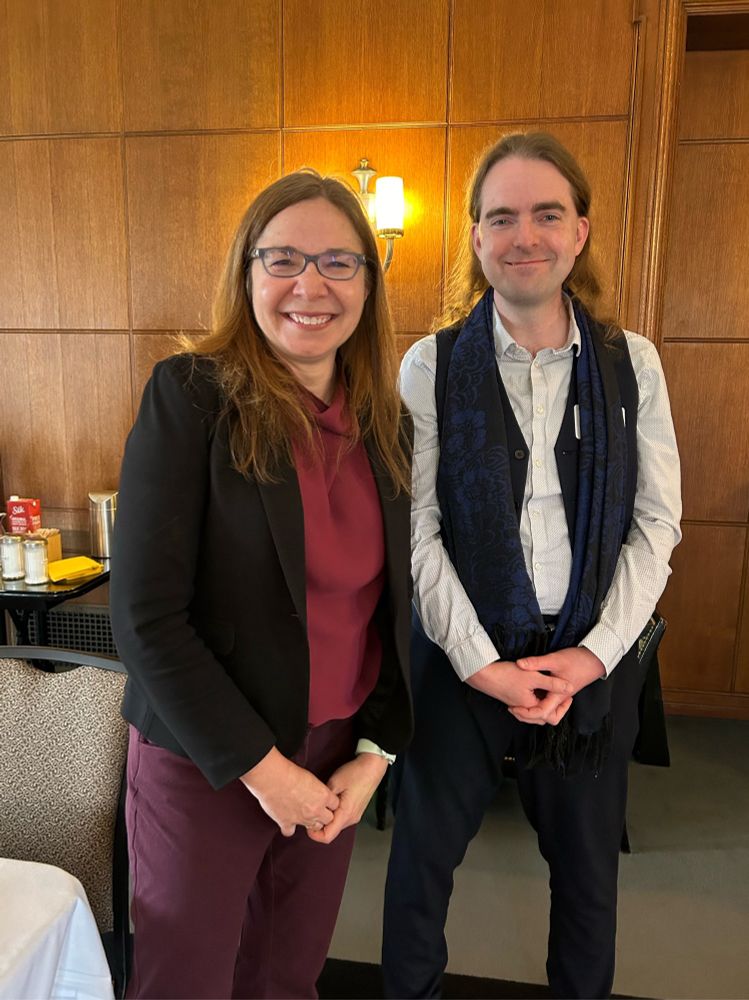 Two people standing next to each other and smiling, looking at the camera