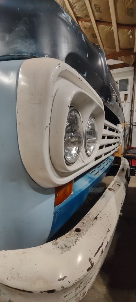 The white, front grill of a blue and black 1959 Ford F-100. 