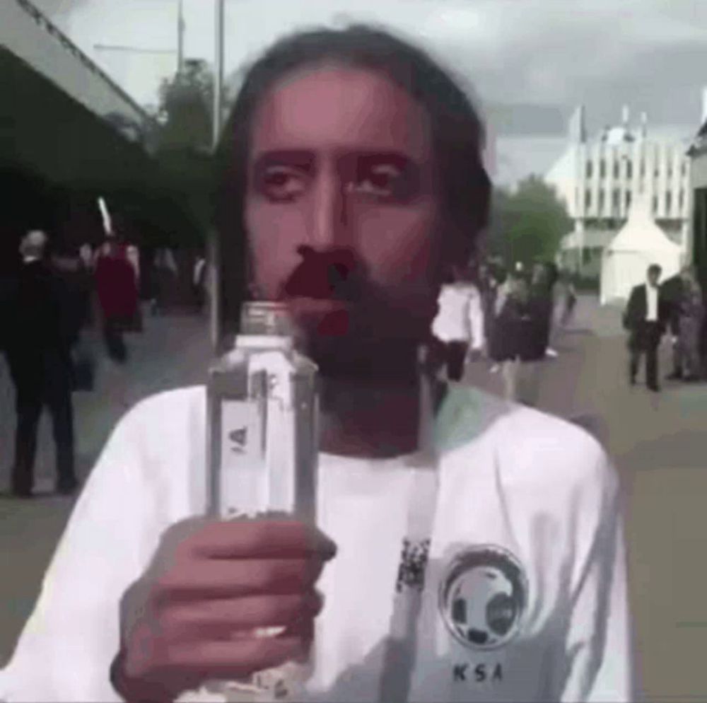 a man is holding a bottle of water in his hand .