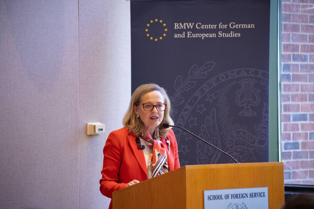 An individual is giving a speech at a podium labeled "School of Foreign Service" with the BMW Center for German and European Studies banner in the background.