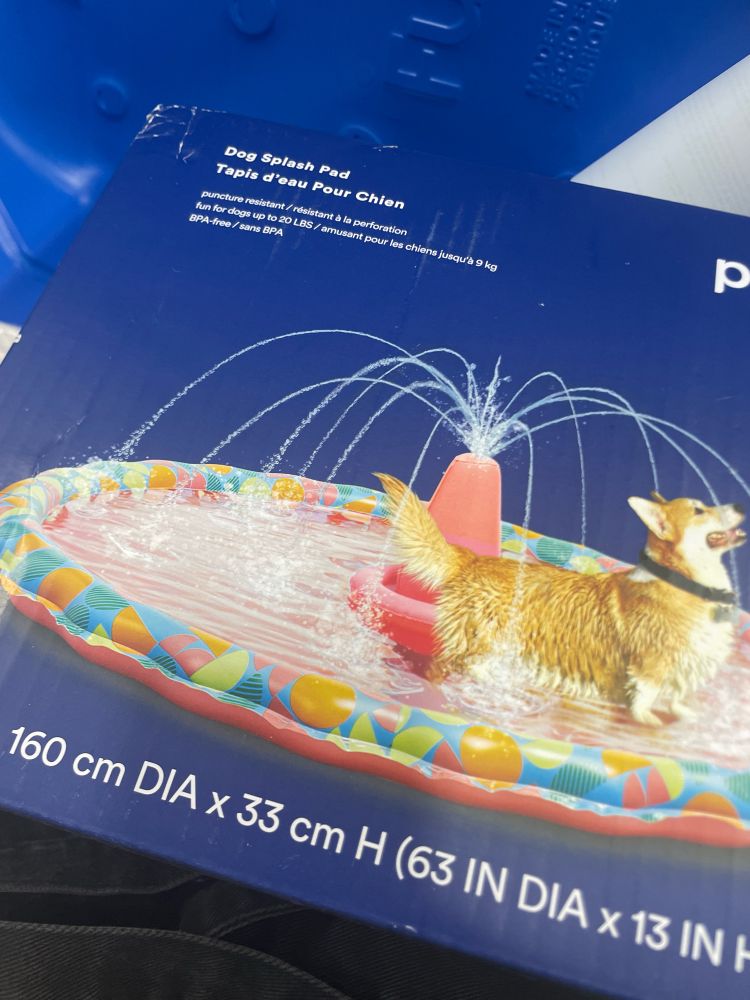 Puppy splash pad box that shows a corgi under a plastic fountain 