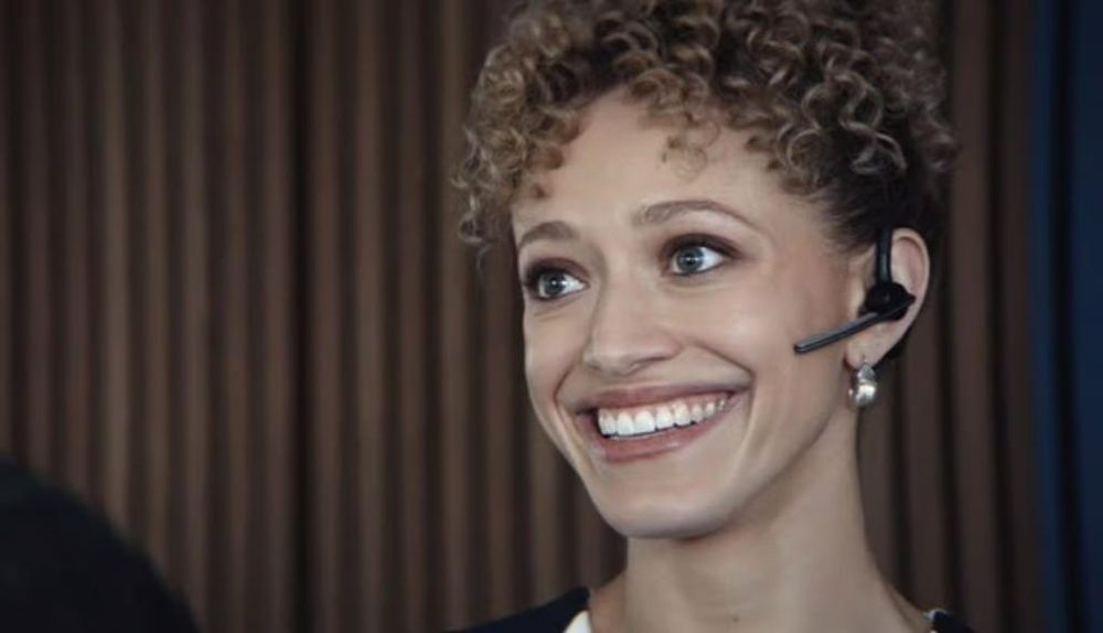 Natalie from Severance - a black woman wearing a headset and giving a creepy smile to the camera 
