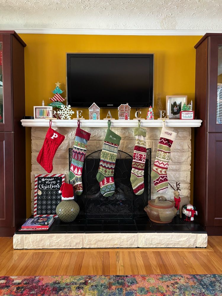 Colorful stockings and Christmas decorations hung by a fireplace. 