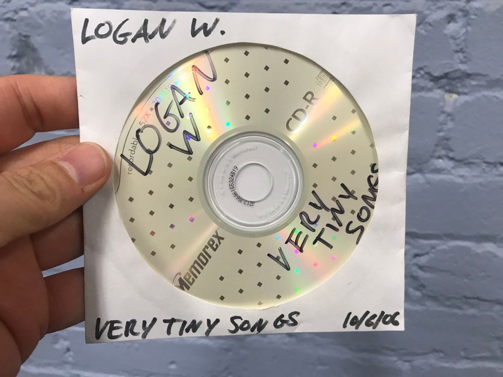 Hand holding a CD-R master of Very Tiny Songs by Logan Whitehurst. This handwriting doesn’t look like his but honestly his physical abilities were diminishing by the end of this project. I’ve asked around and no one recognizes this handwriting as any of the other 3 people who could have possibly burned this disc. 