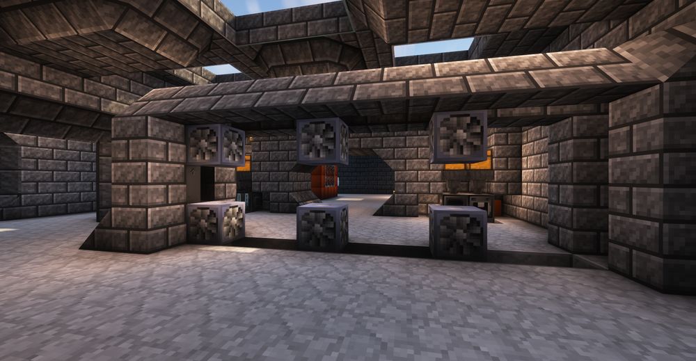 a screenshot of modded minecraft showing a stone brick workshop being built, with a central island jutting from the rightmost wall, opposite a wide entranceway. In the island are 6 metal blocks with spinning fans, turbines for generating electricity in the modset being played.

The ceiling has a cross of skylights just visible at the top of the image. The room is bright and seems to be lit by invisible pointlike sources.