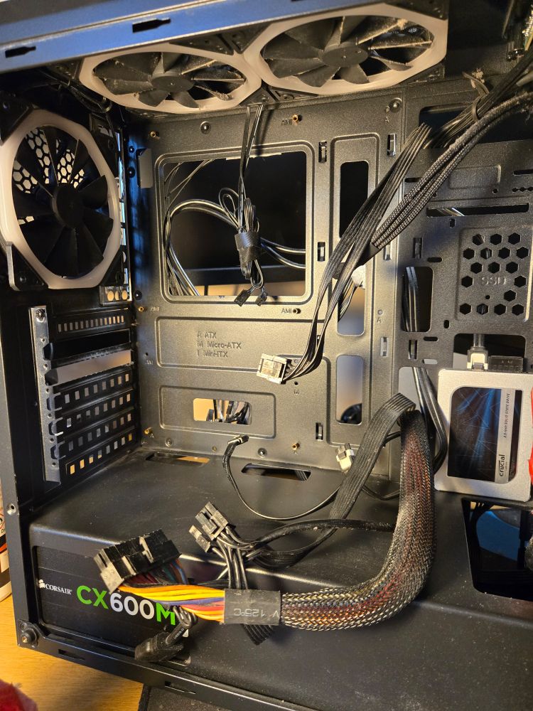 The same PC case, motherboard removed, disconnected wires hanging loose