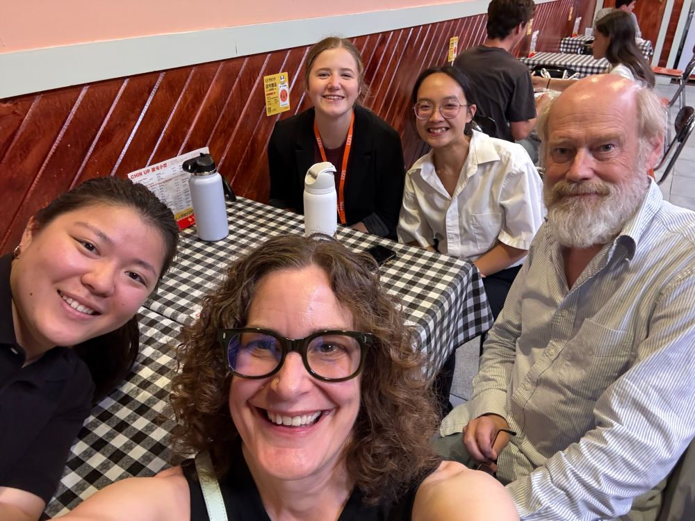Selfie of five WashU scientists smiling and waiting for their dinner