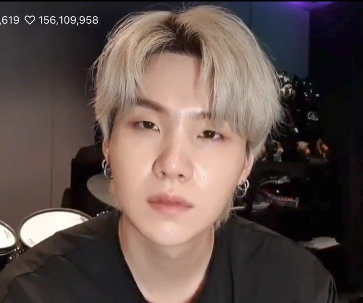 yoongi with blonde hair wearing a black t-shirt on weverse live. he was trying to read the livechat, i guess.