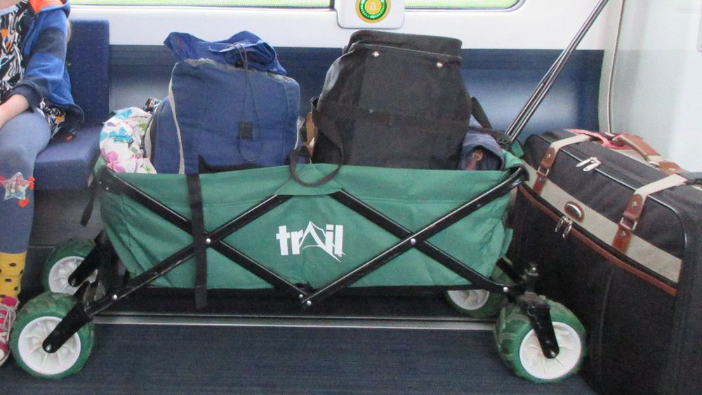 A festival-style trolley on a train, with multiple small bags packed inside it