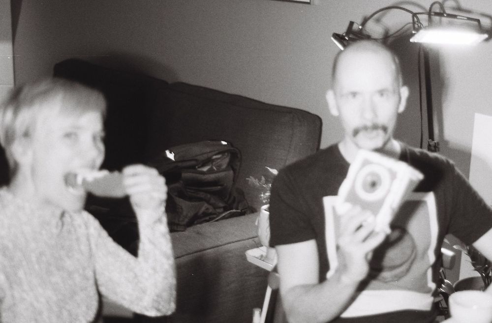 Yvonne and I eating the first gingerbread camera at the table where I was simultaneously constructing the first.
