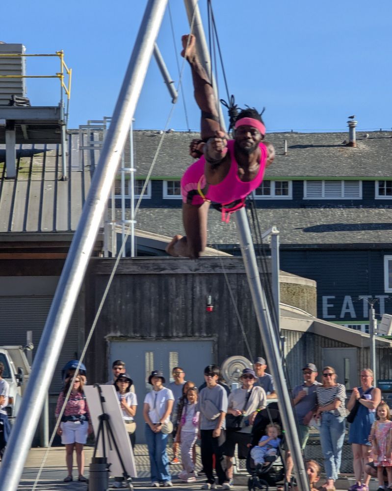 Cuream Jackson from Up Up Up Inc. spinning during an aerial event at the Seattle Waterfront Park on August 10, 2025. Cuream is wearing hot pink shorts, a tank top and sweatband in high temperatures across from the Seattle Aquarium. The aerial show was sponsored by 4 Culture.