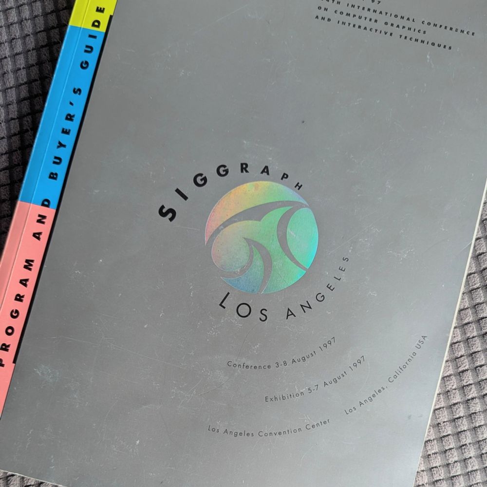 The front cover of the Program and Buyer's Guide from SIGGRAPH 97, the 24th International Conference on Computer Graphics and Interactive Techniques. The conference was held August 3-8, 1997 at the Los Angeles Convention Center in Los Angeles, California USA. The book is grey with black text. The spine has three blocks of color: lime green at the top, royal blue in the center, and peach at the bottom. This was an exciting time to be a 3D animator. Motion capture suits were introduced and demonstrated, changing the world of animation forever by helping 3D animation become more realistic.