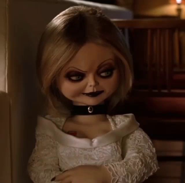 a doll with a choker around her neck is sitting on a chair