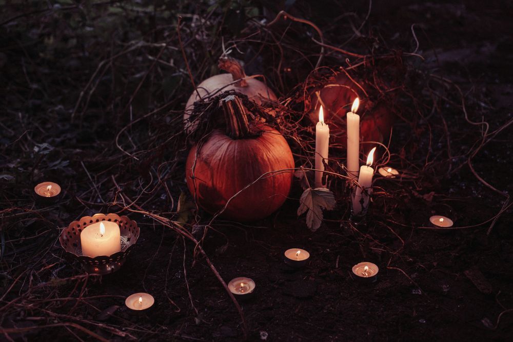 On a dirt and vine coated ground tea lights, candles, and pumpkins are put into an aesthetically pleasing display.

Photo by freestocks on Unsplash.