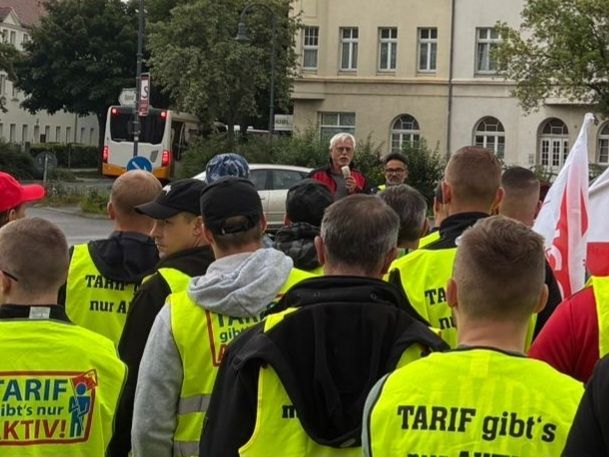 Streikkundgebung. Menschen hören einem Redner zu.