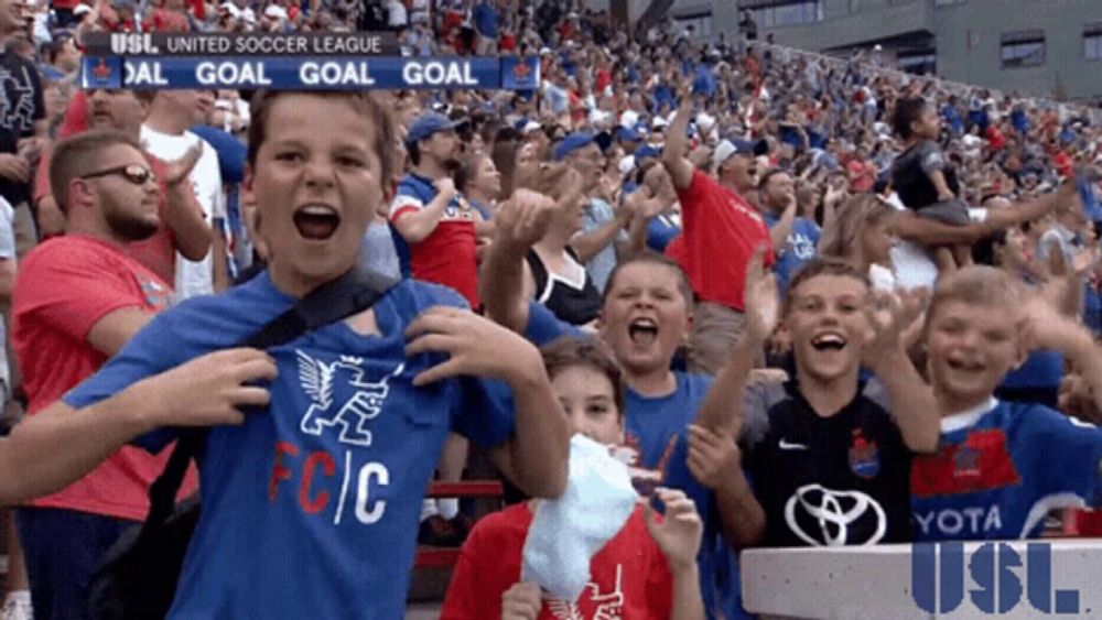 a boy wearing a shirt that says fc / c stands in a crowd