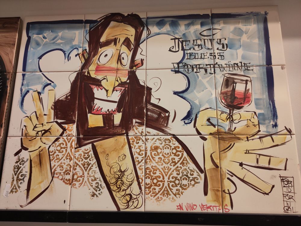 A picture made of tiles showing Jesus with a glass of wine in his hand and the words "Jesus bless portwine".