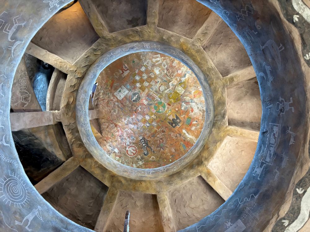 Painted ceiling with Native American-style pictographs and carvings, seen from below.