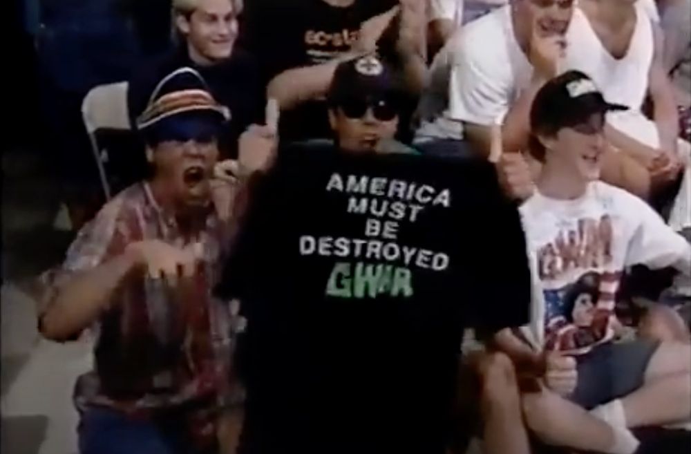 some terrible white 80s orange county bros at the wally george show the one on the left is wearing a visor and yelling, the middle guy's got a hat and sunglasses and is holding an "america must be destroyed gwar" shirt and the guy next to him looks a bit like zuck and is wearing a gear t-shirt