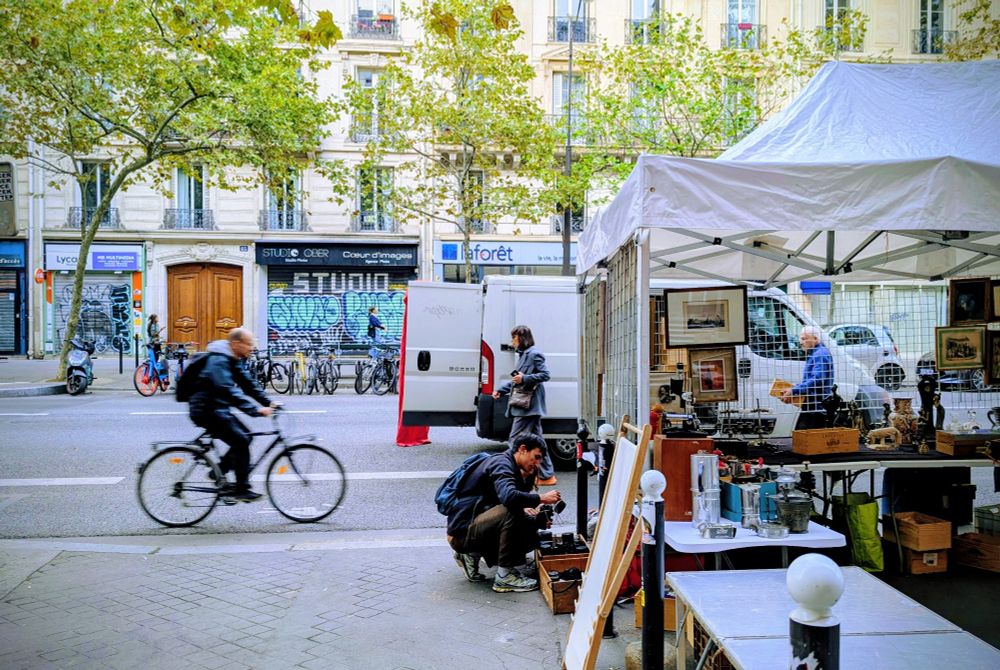 Des cyclistes passent sur la piste cyclable à côté de la brocante boulevard Voltaire 
