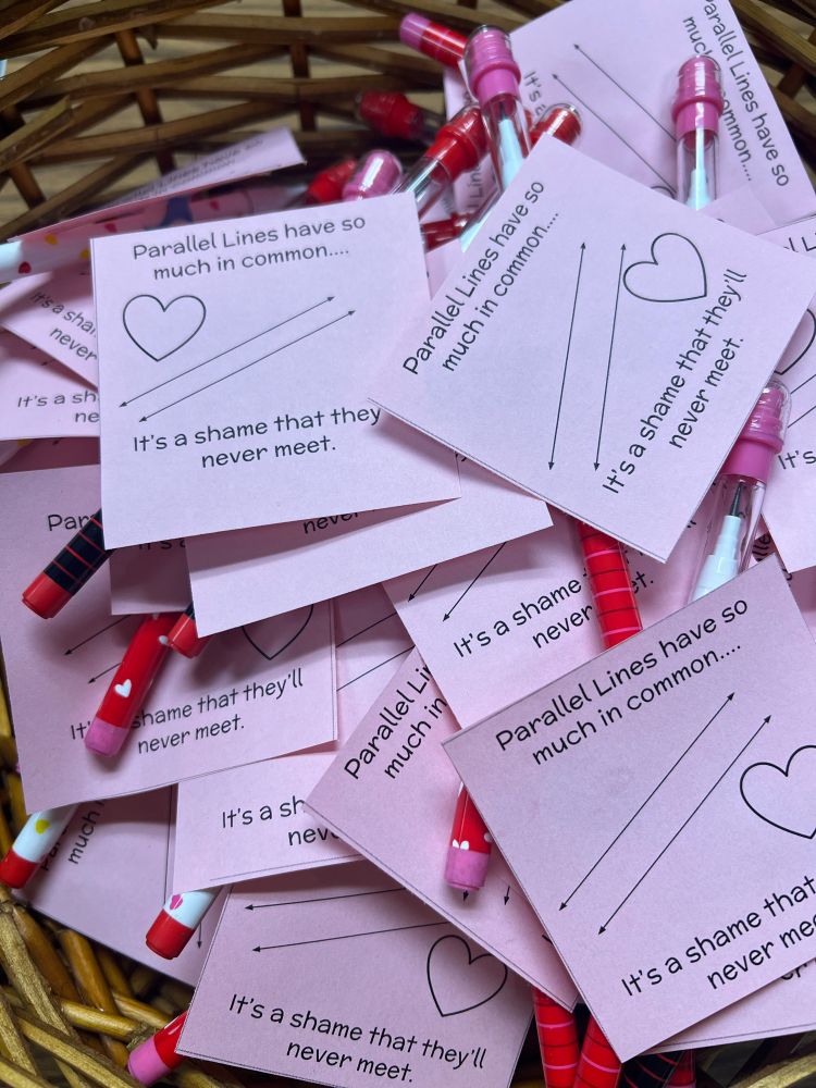 Basket full of pink valentines taped to pencils that say “parallel lines have so much in common… it’s a shame that they’ll never meet”
