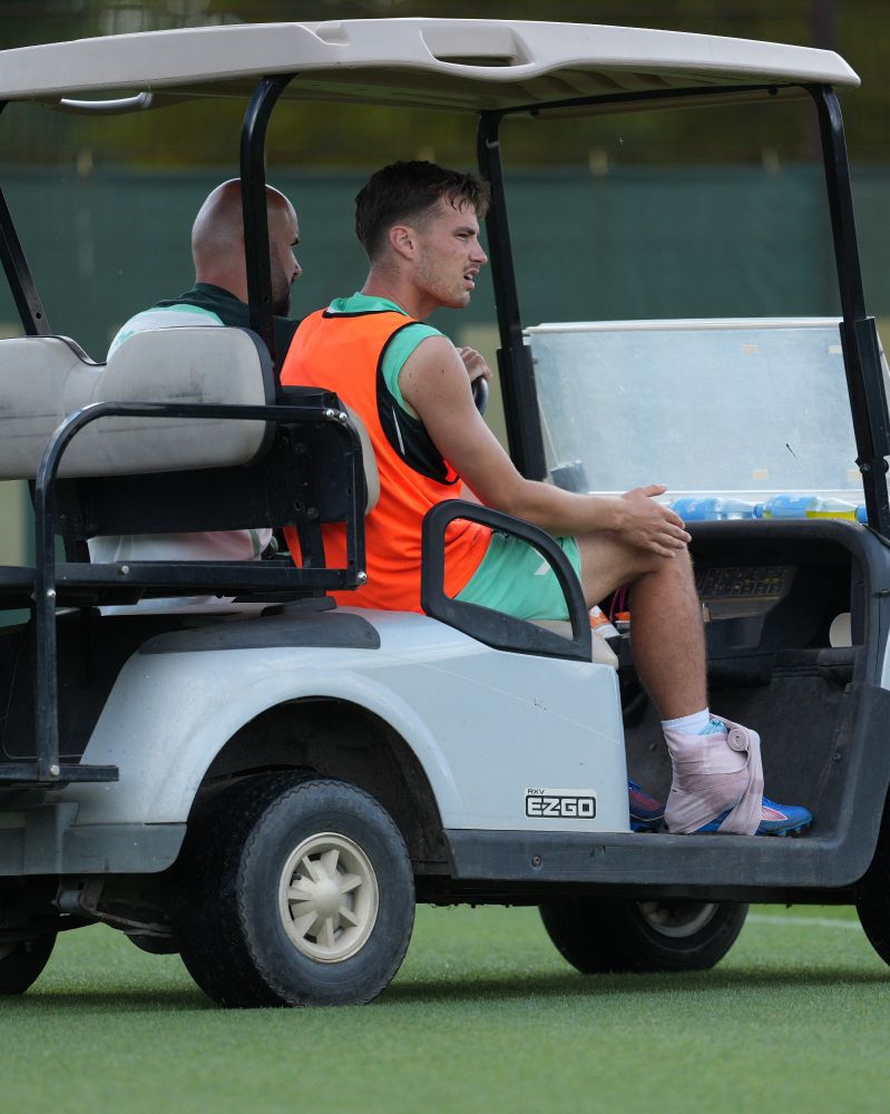 Deman wird mit dem Golkart weggefahren und hält sich das rechte Knie