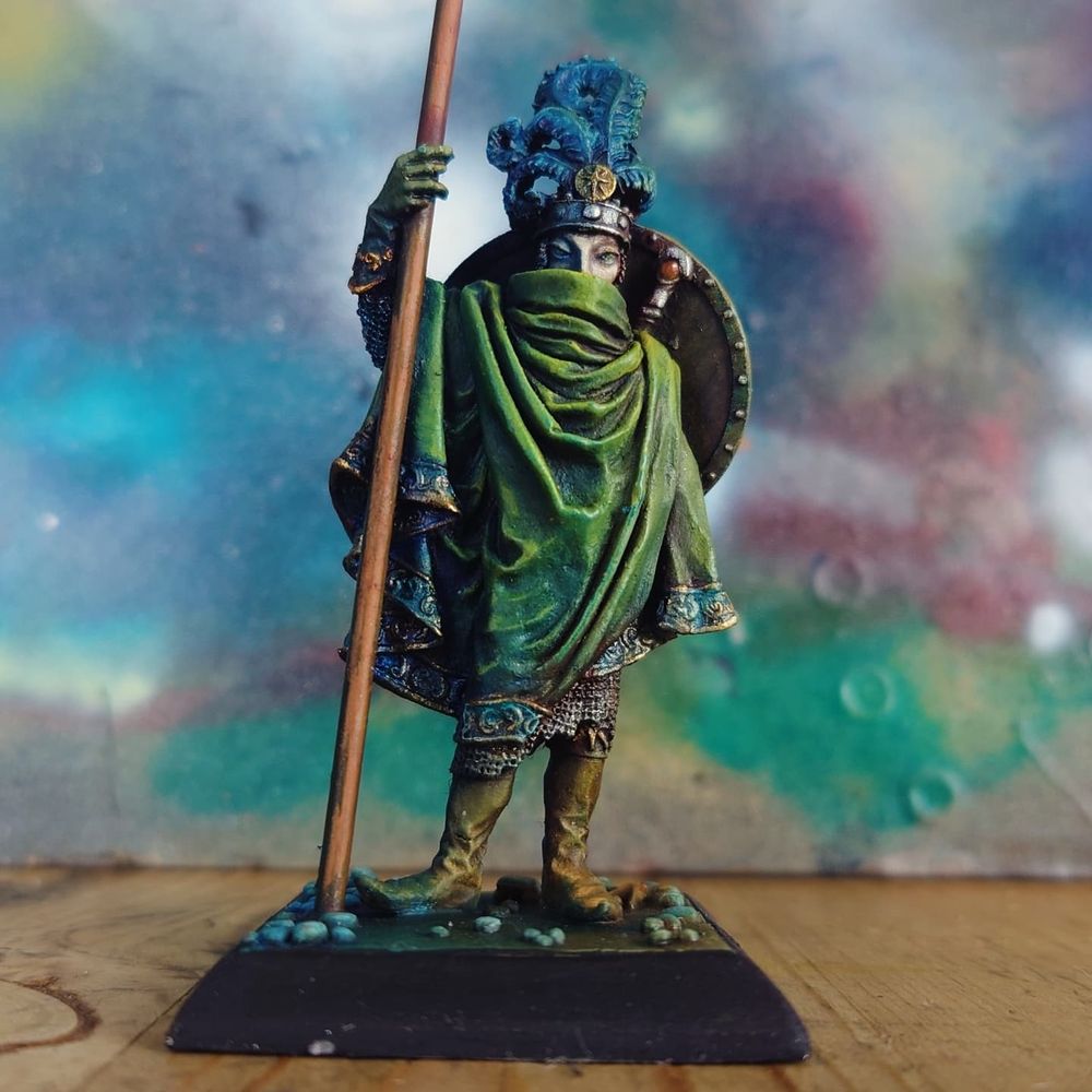 a 54mm miniature of an elf king in a green cloak, holding a long halberd, painted with artists' oil paints. this model is the Sea Elf Lord by Thunderbolt Mountain Miniatures, c.1991. 