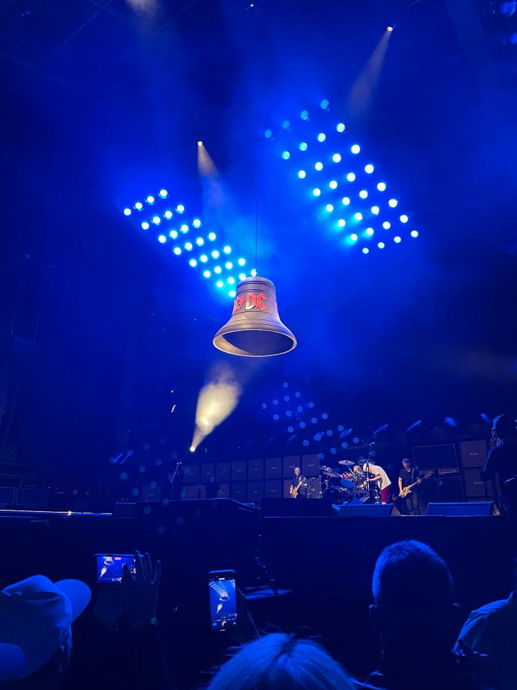 A large bell with the AC/DC logo on it, hanging over a stage