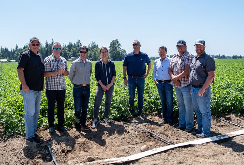Director Casey Sixkiller stands with Ecology staff and members of the Whatcom Ag Water Board with a field in the background. 