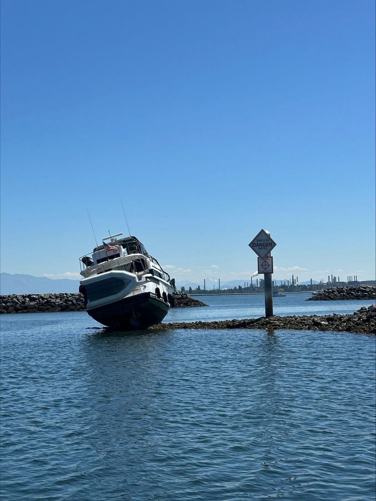 A 40-foot pleasure craft grounded on rocks at Cap Sante Marina, leaning to one side.