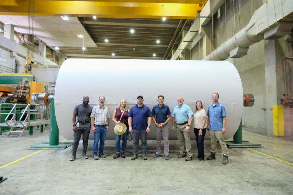Director Casey Sixkiller stands with Ecology staff and staff from Inland Empire Paper near a large drum during a tour of the Inland Empire Paper facility. 