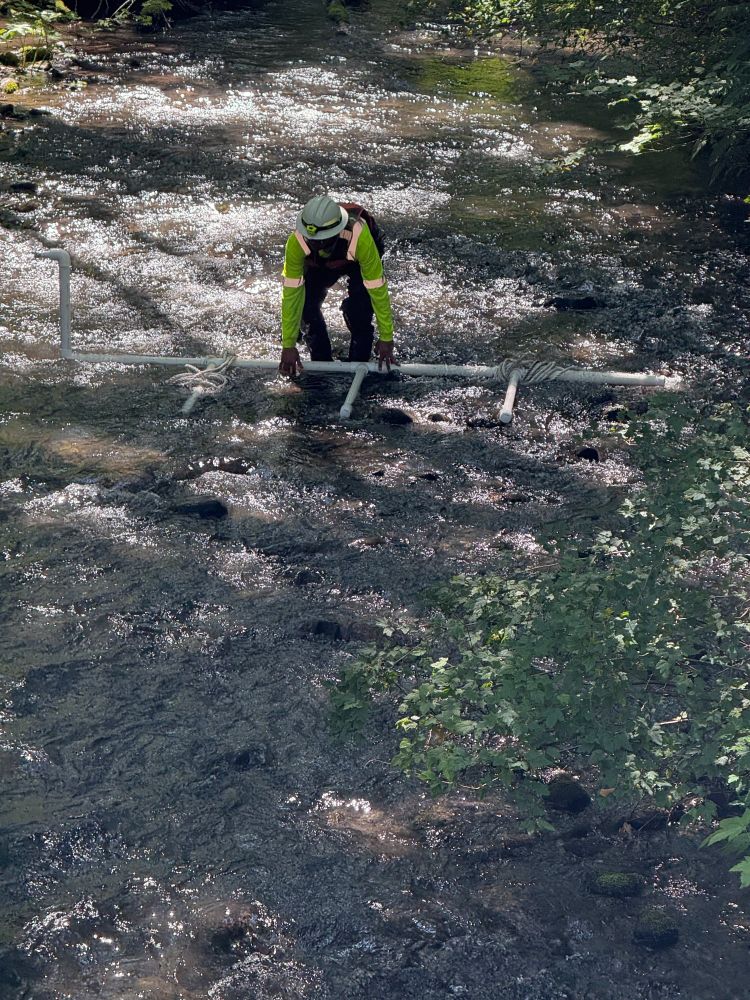 Responder performs sparging in Indian Creek, a technique used to agitate and release fuel trapped under debris or rocks so it can be collected with absorbent materials