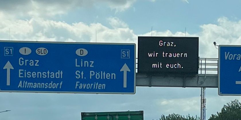 Autobahn-Tafel-Einblendung. Graz, wir trauern mit euch.